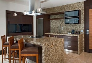 Una cocina moderna con encimeras de granito, electrodomésticos de acero inoxidable y una isla integrada con taburetes de bar.