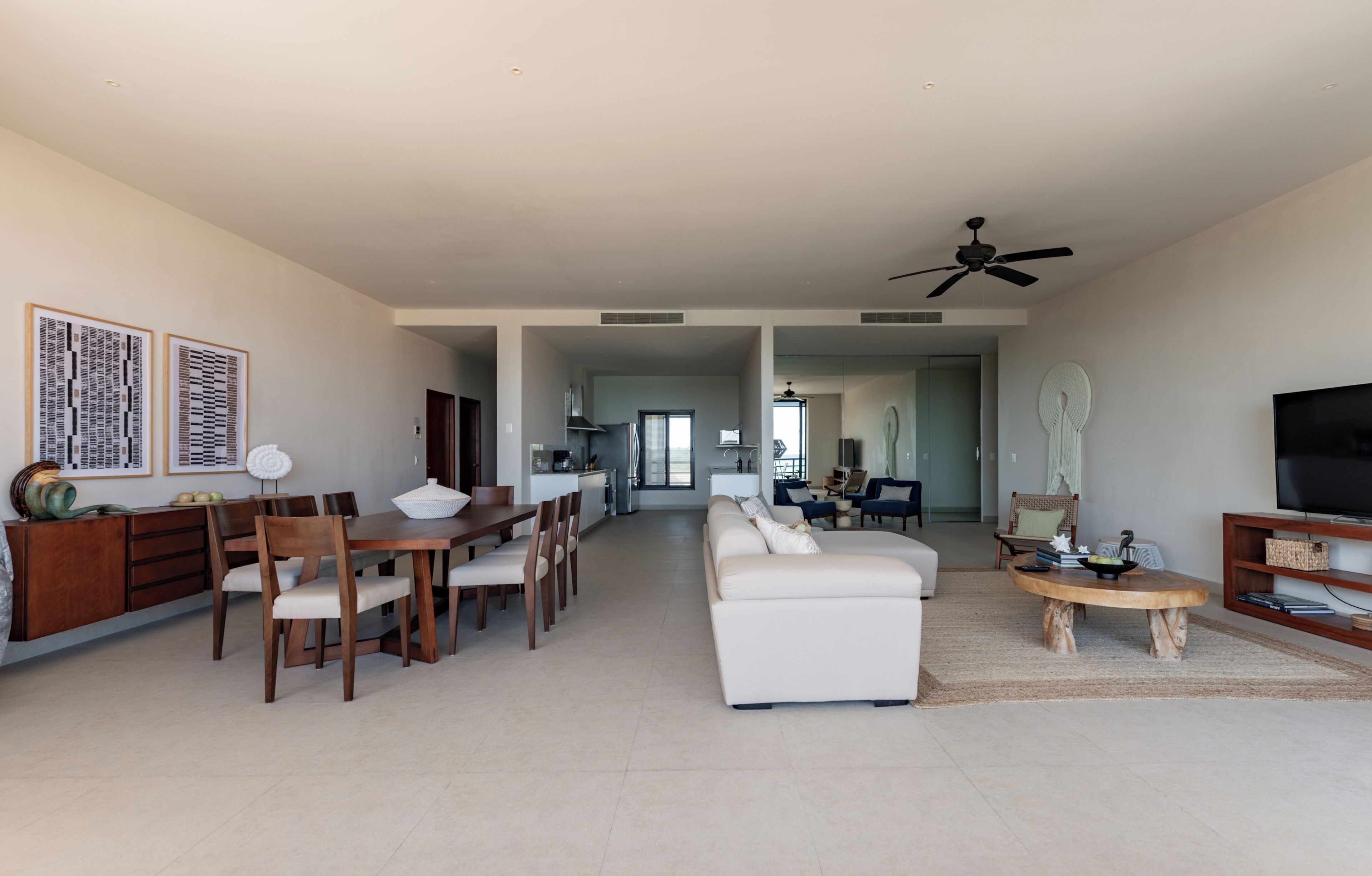 A spacious living room with a dining area, a sofa, a TV, and a ceiling fan.