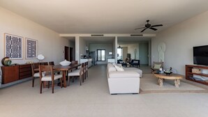 A spacious living room with a dining area, a sofa, a TV, and a ceiling fan. - Exclusive Penthouse, beach front & Cleaning Included In Bahia Tankah Tulum (Tulum)