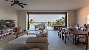 Ein modernes Wohnzimmer mit großem Fernseher, einer Couch, einem Esstisch und Stühlen.