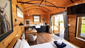 A cozy cabin with a wooden interior, a bed, a dining area, and a kitchen.