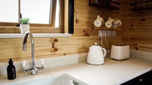 A kitchen with a white countertop, a stainless steel faucet, a white kettle, and a toaster.