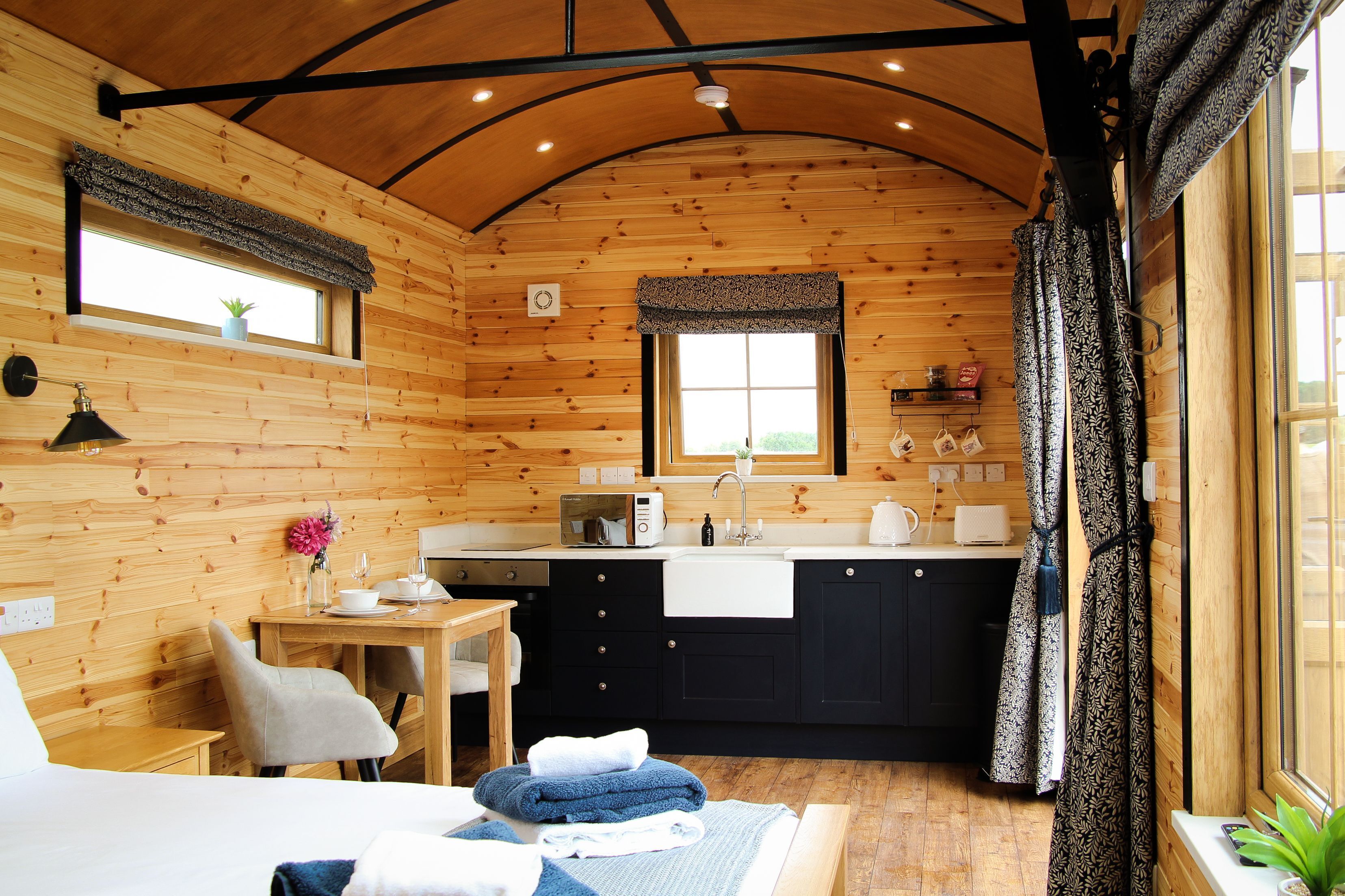 A wooden cabin with a kitchen, dining area, and a bed.