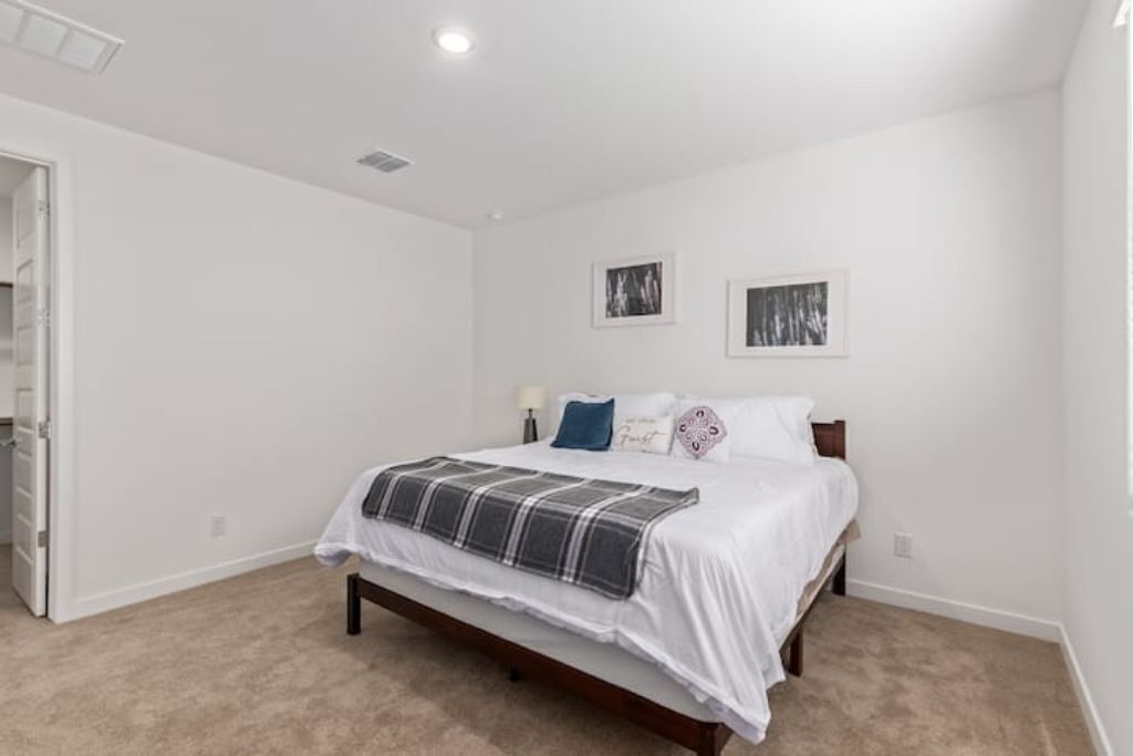 A bedroom with a bed, a door, and two framed pictures on the wall.
