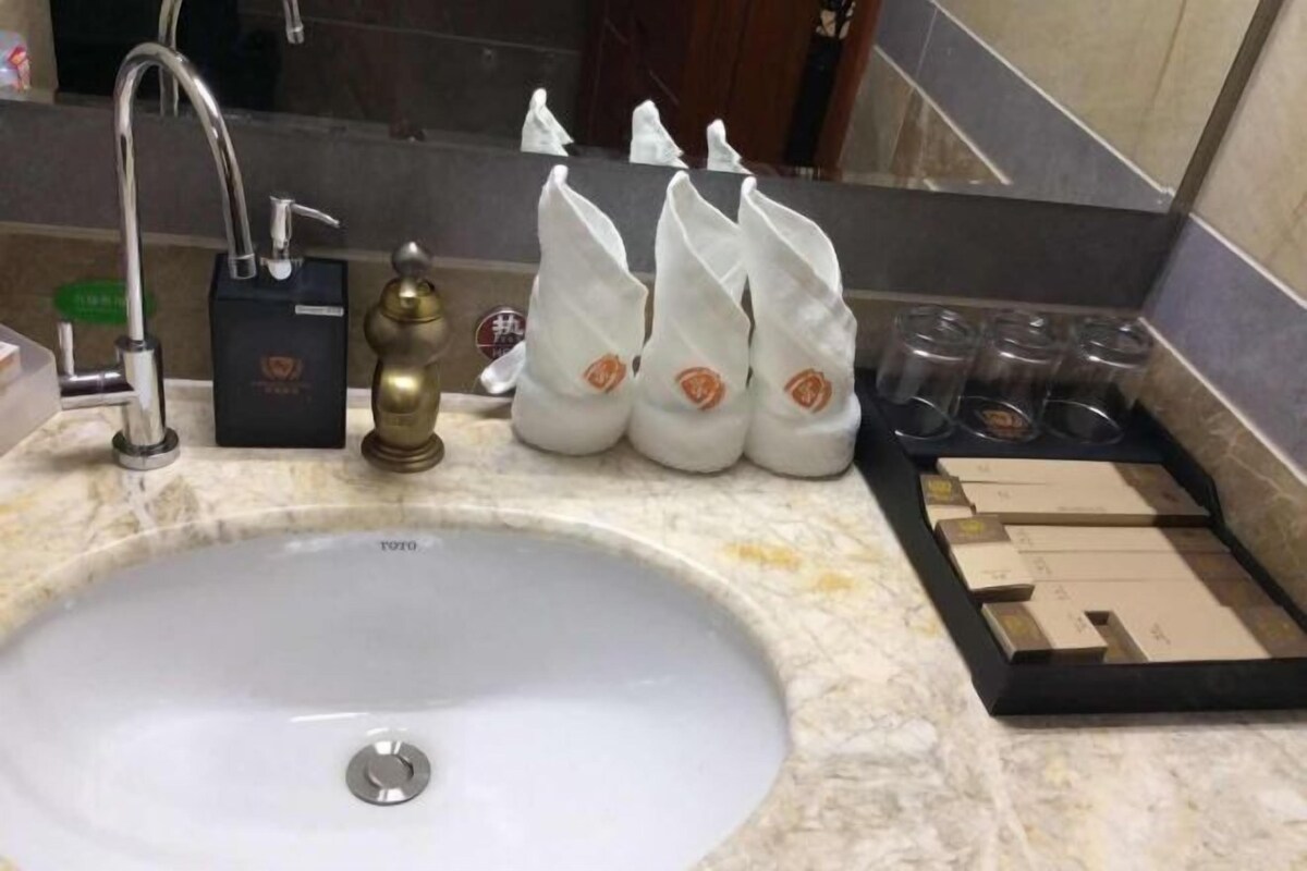 A bathroom sink with a faucet, a soap dispenser, and a set of toiletries including a toothbrush, toothpaste, and a razor.