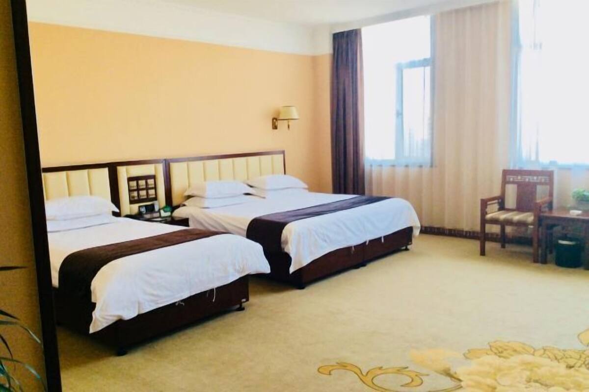 A hotel room with two beds, a desk, and a chair.