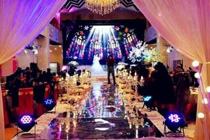 Evento formal con escenario, público y decoraciones florales.