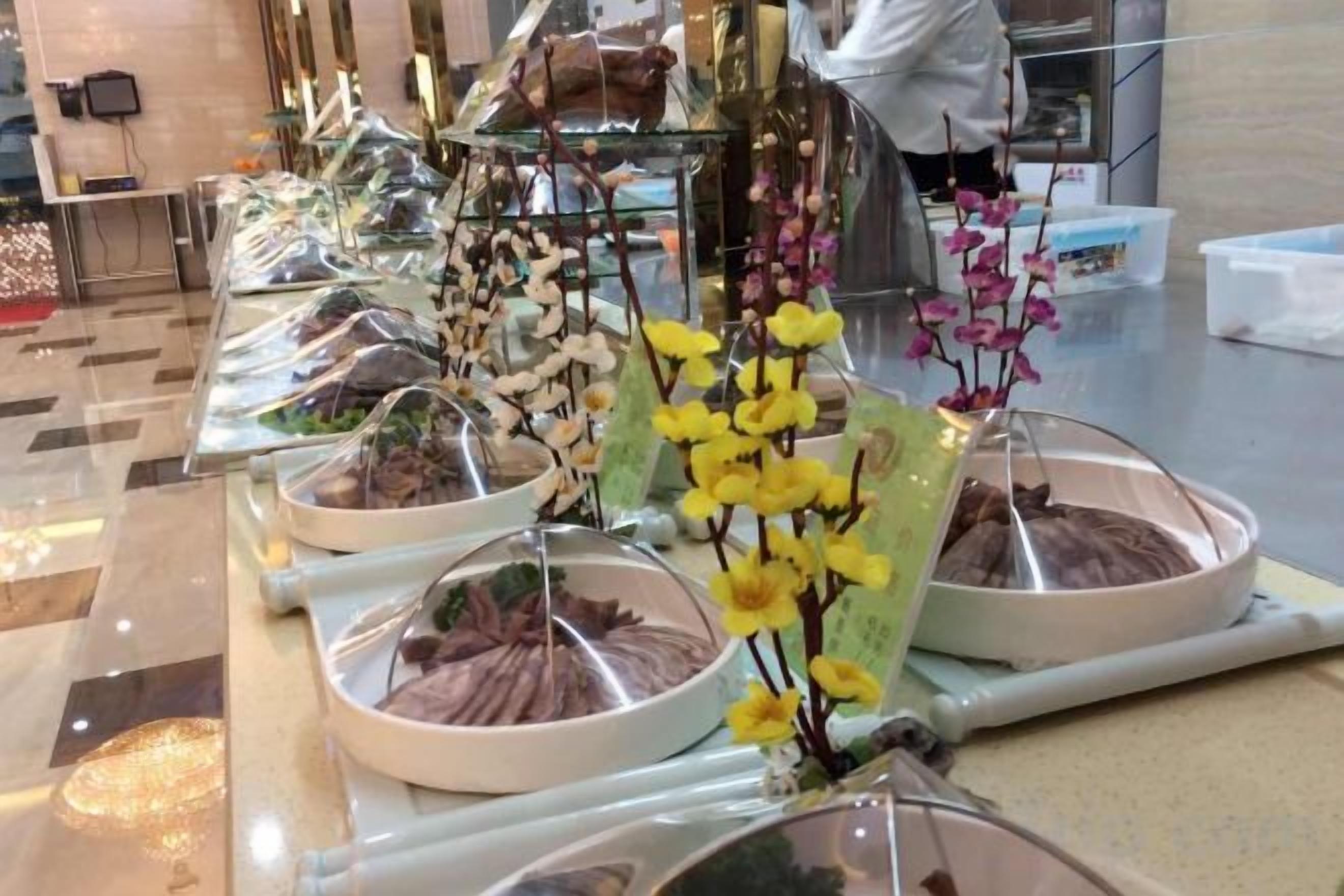 A buffet setup with various food items and decorative flowers.