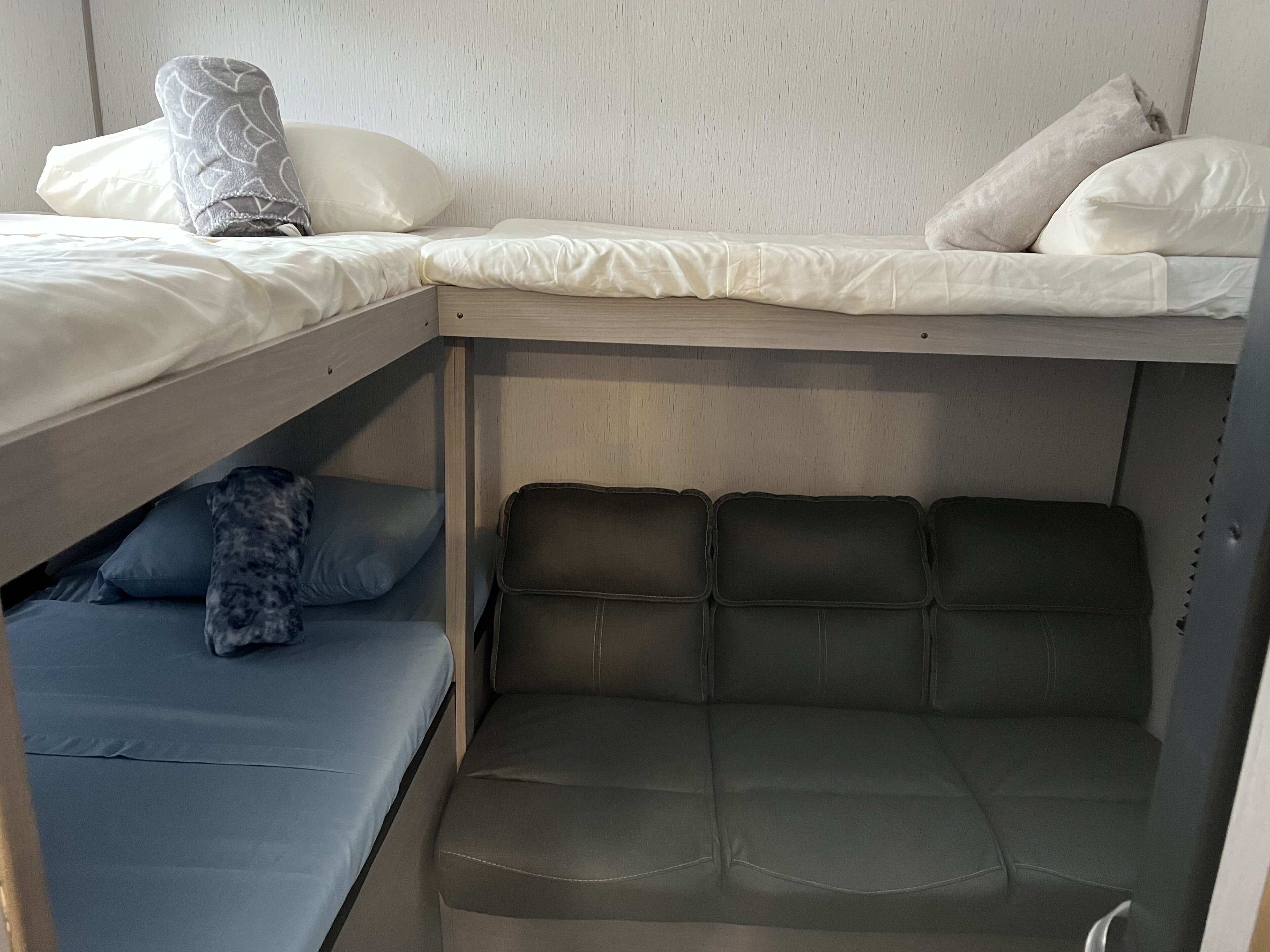 Una cama litera con una cama inferior y un sofá cama debajo.