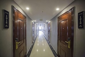 A hotel corridor with wooden doors, numbered room signs, and a polished floor. - Yunduo Hotel (Jinan Jingshi West Road Changqing High Speed Railway Station) (Jinan)