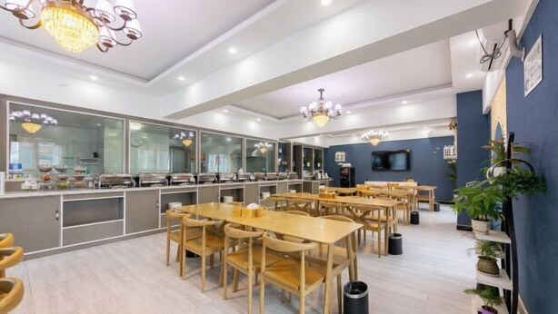 A modern dining area with wooden tables and chairs, a counter with food items, and decorative lighting.