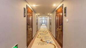 A hotel hallway with wooden doors, a carpet with floral patterns, and a sign indicating room number 1010.