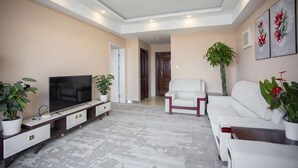 A living room with a flat-screen TV, white sofa, and potted plants. - Yunduo Hotel (Jinan Jingshi West Road Changqing High Speed Railway Station) (Jinan)