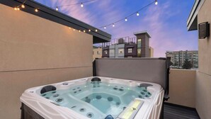 A hot tub on an outdoor balcony with string lights above. - Walk to RiNo’s Best Bars, Restaurants, Coors Field! Rooftop Deck with Hot Tub! (Denver)