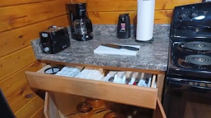 Een keuken met een houten aanrecht, een koffiezetapparaat, een broodrooster, een waterkoker en een fornuis.