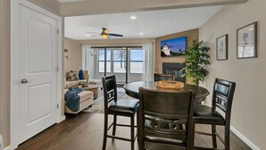 A dining area with a round table, chairs, a ceiling fan, and a wall-mounted light fixture.