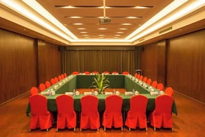 A conference room with a long table, red chairs, and a projector screen. - Houde Hotel (Yifeng)