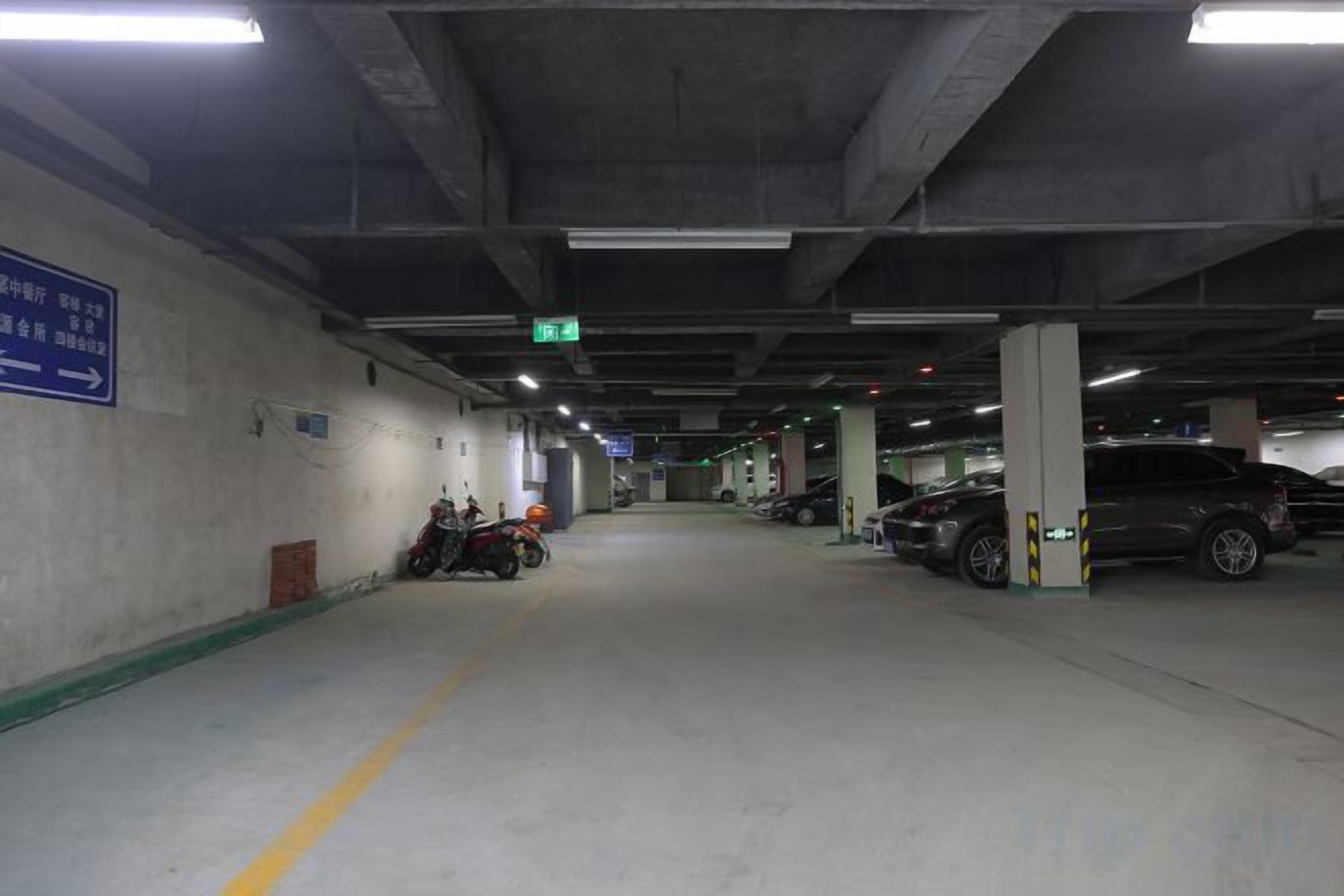 A parking garage with concrete pillars, directional signs, and parked vehicles.