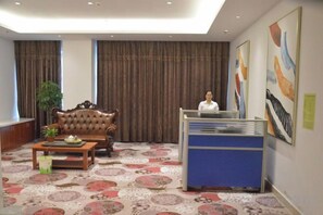 A hotel lobby with a reception desk, a sofa, a coffee table, and a patterned carpet. - Houde Hotel (Yifeng)