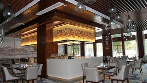 Un restaurante con barra central, varias zonas de estar y un techo con diseño.