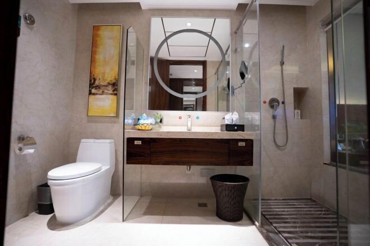 A modern bathroom with a glass shower enclosure, a toilet, and a vanity with a mirror.