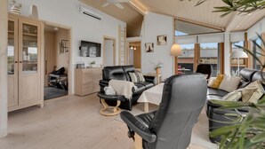 A spacious living room with a black leather sofa, a wooden cabinet, and a television mounted on the wall. - Amazing home in Sydals with WiFi (Sydals)