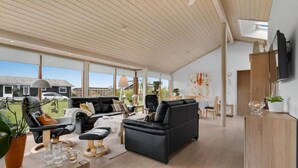 A spacious living area with a high ceiling, a black leather sofa, a wooden dining table, and a view of the outside. - Amazing home in Sydals with WiFi (Sydals)