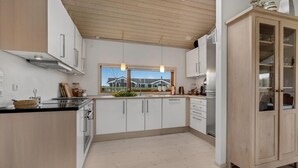 A modern kitchen with white cabinets, a wooden ceiling, and a view of houses through a large window. - Amazing home in Sydals with WiFi (Sydals)