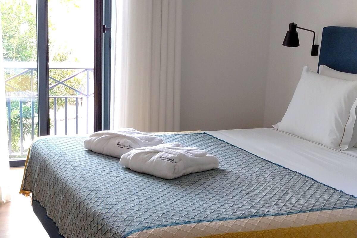 Hotelkamer met een bed, nachtkastje, lamp en uitzicht op de omgeving.