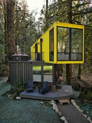 A yellow cabin with a deck, two chairs, and a small table. - Sea Containers-Hot Tub/Steam/Sauna/Cold Plunge (Index)