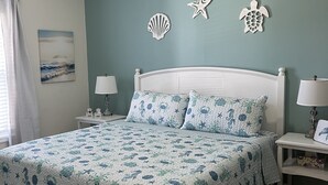 Un dormitorio con cama, mesitas de noche, ventilador de techo y adornos en la pared.