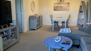 Una sala de estar con televisor, mesa de comedor y sofá.