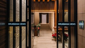 Entrada moderna de hotel com portas de vidro, escada e placa com a inscrição "BRUMMANA VIEWS".