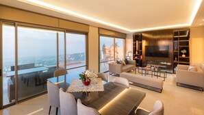 Uma sala de estar moderna com uma televisão grande, assentos confortáveis e uma área de jantar com mesa e cadeiras.