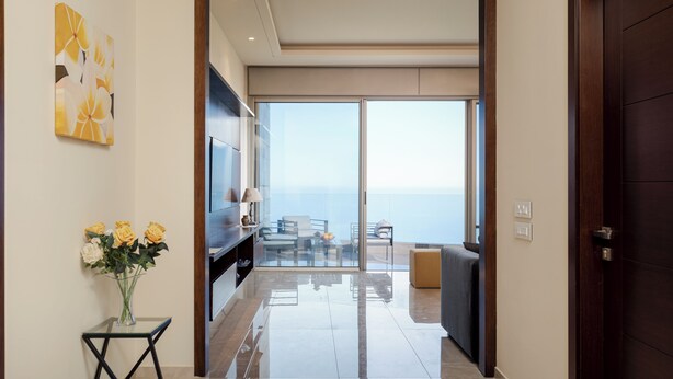 Um interior moderno com uma mesa de vidro, um vaso de flores e vista para o exterior.