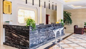 A modern reception desk with a marble top, black pendant lights, and a potted plant. - Hongxin Hotel (Jinggangshan City)