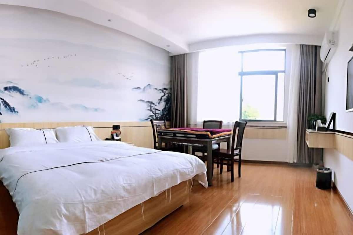 A hotel room with a bed, a desk, and a large window.