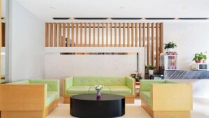 A modern lobby with a reception desk, green sofas, a black coffee table, and a wooden slat wall. - Jinjiang Inn (Shanghai International Tourist Resort Kangxin Highway) (Shanghai)