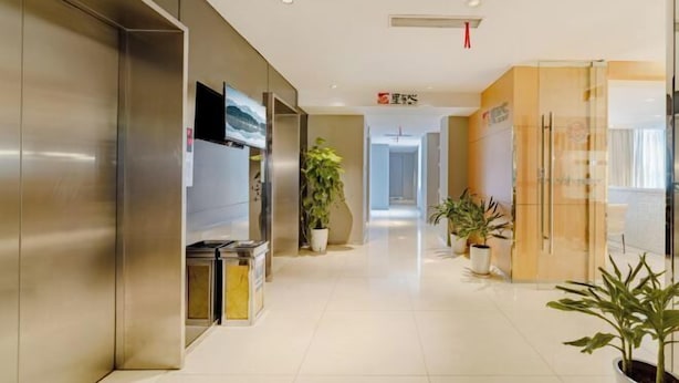 A modern hotel corridor with a clean, polished floor, stainless steel elevator, and potted plants along the walls. - Jinjiang Inn (Shanghai International Tourist Resort Kangxin Highway) (Shanghai)