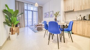 A modern apartment with a dining area, kitchen, and large windows. - Sophisticated 1BR at Town Square Rawda by Deluxe Holiday Homes (Dubai)