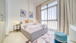 A modern bedroom with a bed, bedside tables, and artwork on the wall. - Sophisticated 1BR at Town Square Rawda by Deluxe Holiday Homes (Dubai)