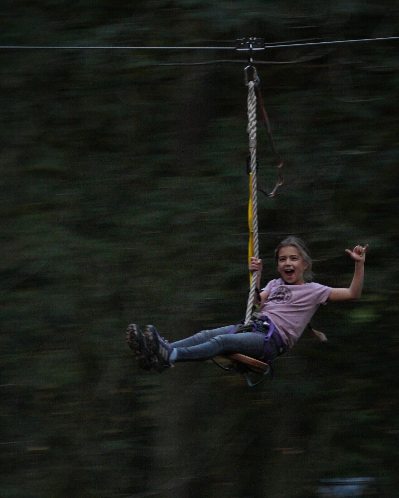 Una persona che sfreccia su una zip line in una zona boschiva.
