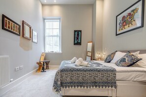 Ein Schlafzimmer mit einem Bett, einem Fenster und gerahmten Kunstwerken an den Wänden.