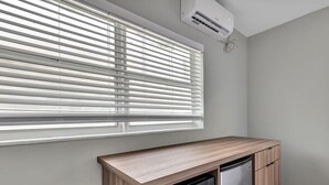 A kitchen with a built-in microwave and oven, a window with blinds, and an air conditioning unit. - 1BR Getaway by Dania & Hollywood Beach (Hollywood)
