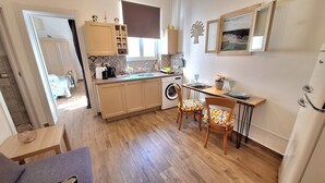 Una cocina funcional con lavadora, una mesa de comedor con sillas y un pequeño rincón de comedor.