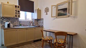 Una cocina con armarios de madera, una cafetera y un comedor con dos sillas.