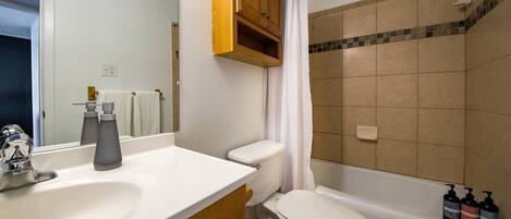 A bathroom with a white sink, a toilet, a bathtub, and a shower curtain.