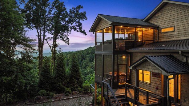 A modern house with a glass extension, surrounded by dense forest. - Modern Mountain Oasis • 5BR with Million-Dollar Lake Views • EV• Hot Tub • PetOK (Blue Ridge)