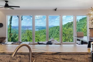 A modern kitchen with a large window overlooking a forested landscape. - Modern Mountain Oasis • 5BR with Million-Dollar Lake Views • EV• Hot Tub • PetOK (Blue Ridge)