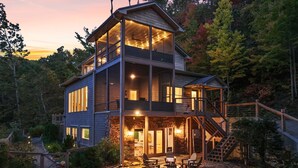 A multi-level cabin with a stone foundation, large windows, and a balcony. - Modern Mountain Oasis • 5BR with Million-Dollar Lake Views • EV• Hot Tub • PetOK (Blue Ridge)